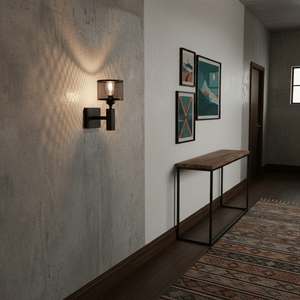 Black mesh wall light casting patterned glow on a textured wall in a hallway with framed art and console table.