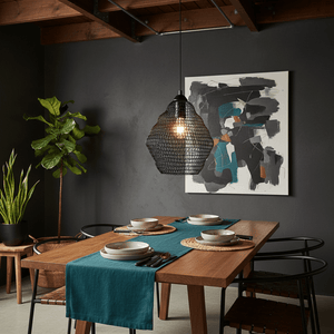 Phantom Black 340 wire mesh pendant light hanging over a wooden dining table set with plates and cutlery.