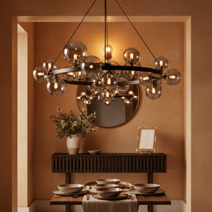 Stylish round bubble pendant light in smoke glass above a dining table set with plates and a vase.