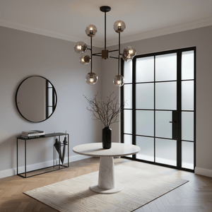 Stylish black and bronze chandelier above a round marble table in a modern interior setting.