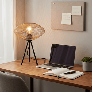 Gold mesh table lamp on a wooden desk beside a laptop and notebook, casting soft light.