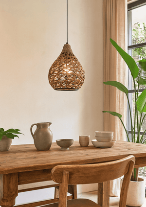 Rustic metal and rope pendant light hanging over a wooden dining table with ceramic dishes.