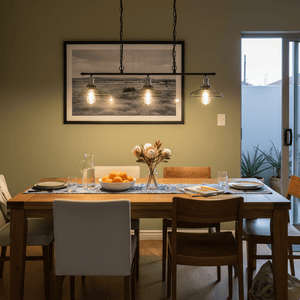3-light black and chrome grid pendant illuminating a dining table with a floral centerpiece and fruit bowl.