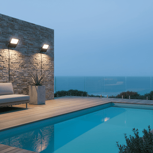 Coastal floodlight illuminating a modern patio area with a pool and ocean view.