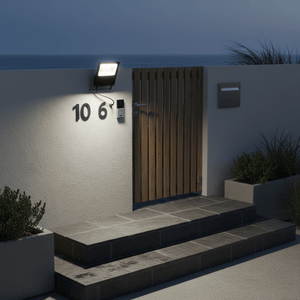 Coastal floodlight illuminating a home's entrance with wooden gate and stone steps at dusk.