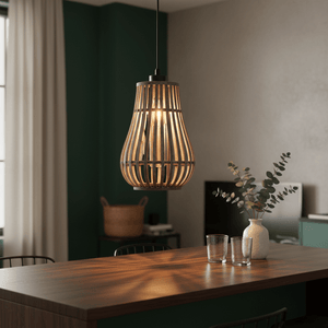 Metal and rattan pendant light hanging above a wooden dining table with glasses and a vase.