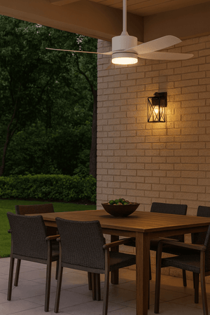 Black down-facing wall lantern glowing above a patio dining table beside a brick wall and garden.