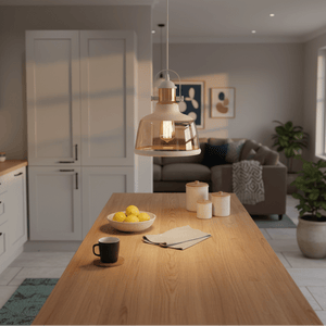 White metal pendant light with cognac glass shade hanging over a wooden kitchen island, surrounded by decor.