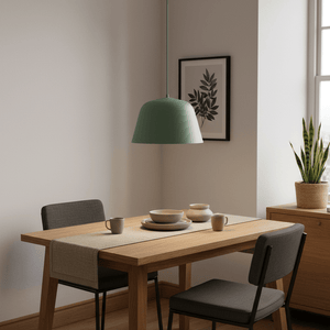 Teal pendant light hanging above a wooden dining table set with dishes and a plant nearby.
