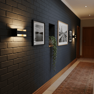 Feloniche LED Wall Light in black and gold illuminating a dark wall with framed artwork and a plant.