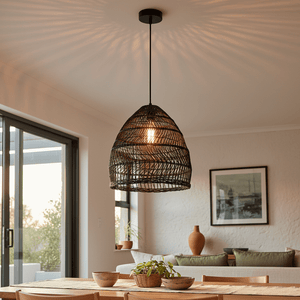 Black rattan pendant light hanging over a wooden dining table, casting warm shadows on the ceiling.