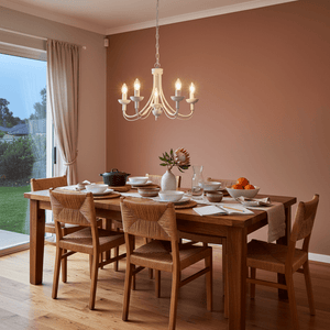 White 5-light chandelier hanging over a wooden dining table set for a meal in a cozy room.