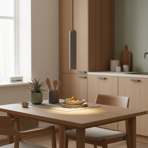 Modern grey pendant light hanging above a dining table with fruit bowl and kitchen backdrop.