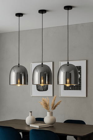 Modern interior with three hanging pendant lights, a table with decorative items, and framed artwork on the wall.