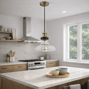 Antique brass pendant light with clear glass shade hanging over a kitchen island with bowls on a wooden tray.