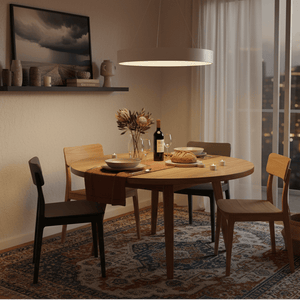 Dining room with a wooden table set for a meal, wine bottle, and flowers, large window showing cityscape.