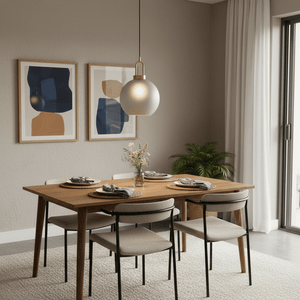 Smoke-grey pendant light with antique brass detailing above a wooden dining table set with plates and flowers.