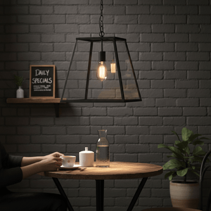 Large rustic rectangular lantern pendant light hanging over a wooden table with coffee and water carafe.