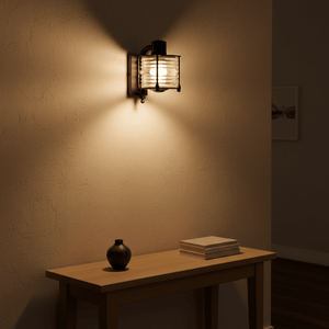Matt black Torbay wall lamp illuminating a textured wall above a wooden table with a vase and books.