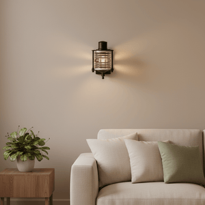 Matt black Torbay wall lamp with decorative glass, mounted above a light-colored sofa with cushions.