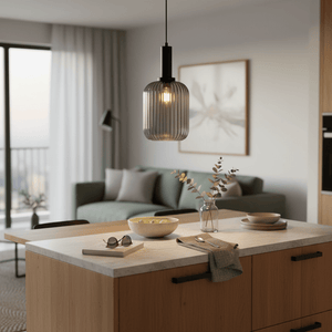 Smoked cut glass pendant light hanging over a kitchen island with a bowl of limes and decorative items.