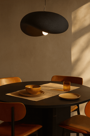 Obsidian Drift 700 Pendant Light hanging above a dining table set with bowls and a glass.