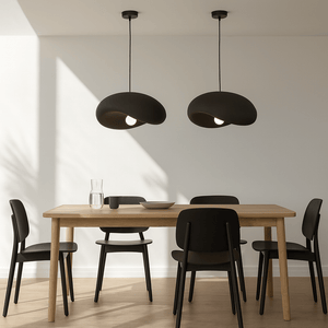 Two Obsidian Drift 500 Pendant Lights hang above a wooden dining table with black chairs, creating a modern ambiance.