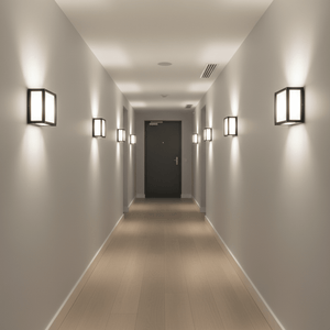 A modern hallway featuring multiple black Cube Outdoor Wall Lights illuminating the space with a soft glow.