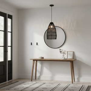 Black rattan pendant light hanging above a wooden console table with a round mirror and decorative items.