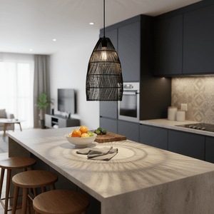 Black rattan pendant light hanging above a kitchen island with a bowl of fruit and a textured countertop.