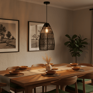 Black Rattan Pendant 280 hanging above a wooden dining table set with bowls and a vase, creating a warm ambiance.