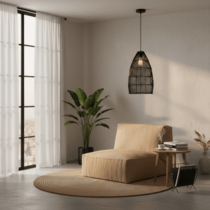 Black rattan pendant light hanging above a cozy lounge chair and side table with plants and natural light.
