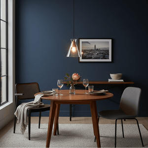 Stylish Black & Gold pendant light hanging over a wooden dining table set with glassware and flowers.