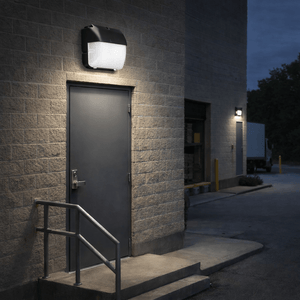 LED wall pack mounted above a door, illuminating the entrance area with focused light.