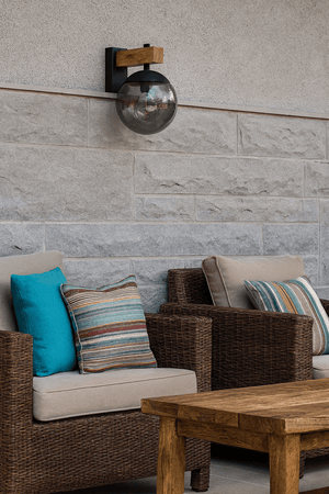 Bufalata Outdoor Wall Light mounted on a textured wall above a cozy seating area with cushions.