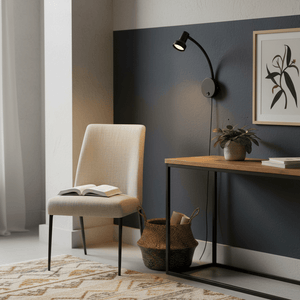 A stylish metal wall light with a flexible arm illuminating a cozy reading nook with a chair and table.
