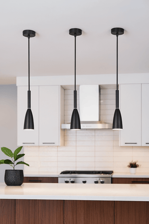 Modern kitchen with black pendant lights, white cabinets, and a tiled backsplash.