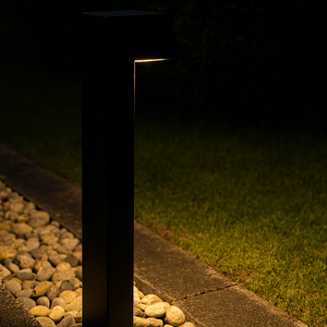 Modern outdoor light fixture on a pebble path at night