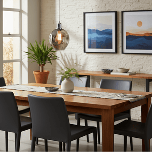 Polished chrome pendant light with smoke glass shade hanging over a wooden dining table in a modern setting.
