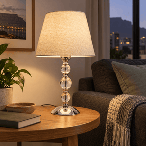 Myrna Satin Chrome Table Lamp with Hessian Shade — on an oak side table beside a charcoal sofa