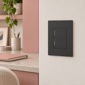 Veti 2 Charcoal Two Lever Wall Switch in a realistic clay-pink desk area setting