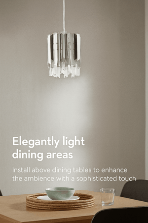 Modern pendant light fixture hanging above a dining table with a neutral background.