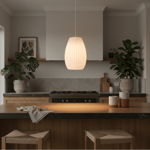 A white 3D printed pendant light hangs above a wooden kitchen island, surrounded by plants and decor.