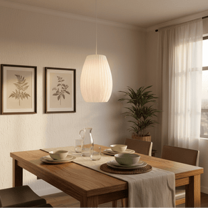 A white 3D-printed pendant light hangs above a wooden dining table set with plates and glasses.