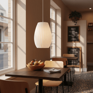 3D printed white pendant light hanging above a wooden table with a bowl of fruit in a cozy interior.