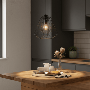 Black metal pendant light hanging above a wooden kitchen table set with cups and flowers.
