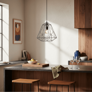 Black metal pendant light hanging above a kitchen island with wooden stools and a bowl of lemons.