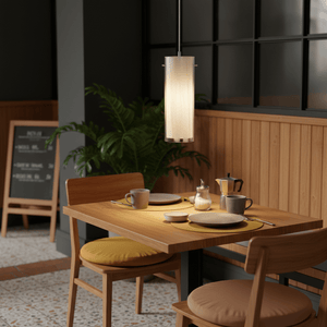 Stylish double glass pendant light hanging above a wooden dining table set with dishes and drinks.