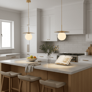 Modern kitchen featuring two Catalina Single Gold Pendant Lights above a countertop with a fruit bowl and an open book.