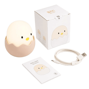 A soft, egg-shaped night light with a smiling face, placed next to a user manual and USB charging cable, all on a white background.